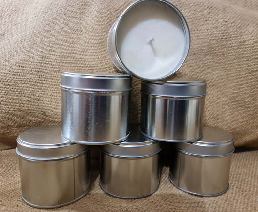 four tins of candles with a white candle in each
